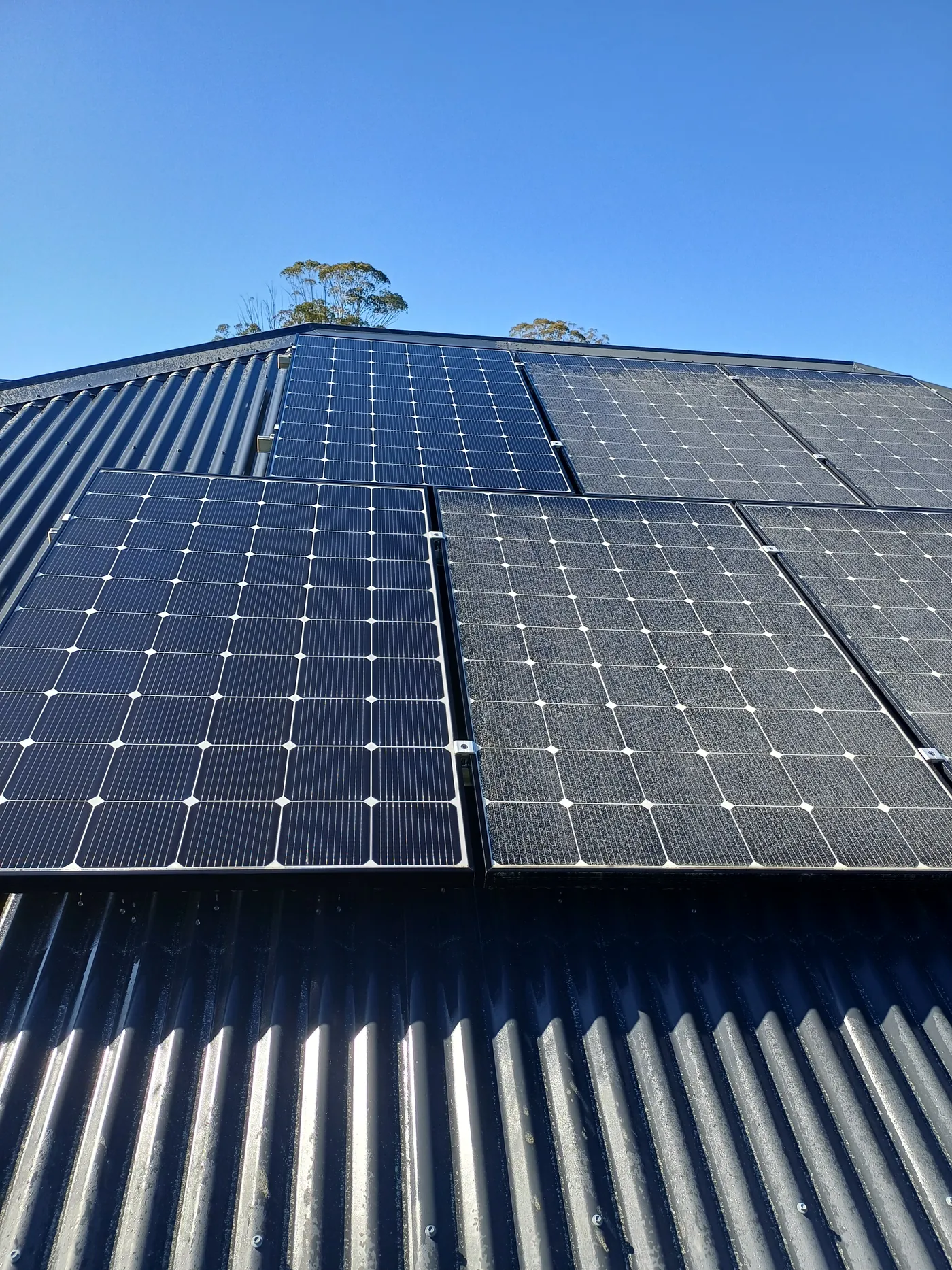 Solar panels cleaned on a corrugated roof under blue sky